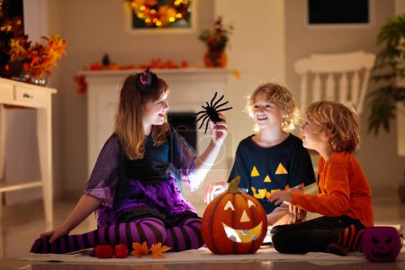 Photo for Little girl and boy in witch costume on Halloween trick or treat. Kids holding candy in pumpkin lantern bucket. Children celebrate Halloween at decorated fireplace. Family trick or treating. - Royalty Free Image