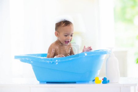 Photo for Baby boy in bath. Mother washing infant child. Cute little toddler playing with soap foam in white sunny bathroom. Water fun. Hair and skin care for young kids. Shampoo and body lotion. Bath toys. - Royalty Free Image