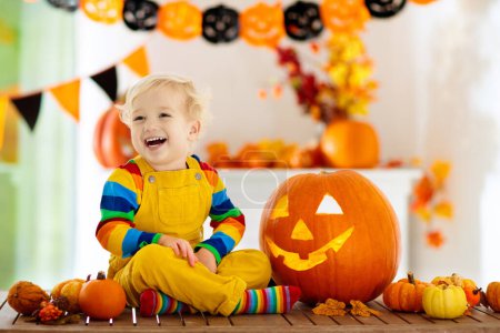 Photo for Little boy in witch costume on Halloween trick or treat. Kids carving pumpkin lantern. Children celebrate Halloween at decorated fireplace. Family trick or treating. - Royalty Free Image