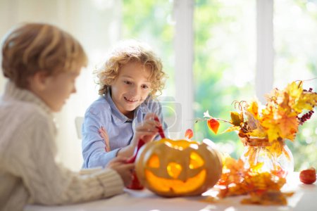 Photo for Family carving pumpkin for Halloween celebration. Boy and girl child cutting jack o lantern for traditional trick or treat decoration. Kids decorate home. Children carve pumpkin. Spooky Halloween fun. - Royalty Free Image