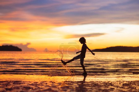 Photo for Child playing on ocean beach. Kid jumping in the waves at sunset. Sea vacation for family. Little boy running on exotic island during summer holiday. - Royalty Free Image