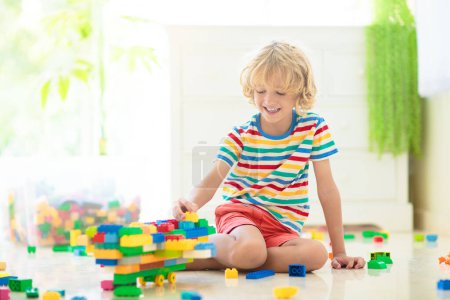 Photo for Kids play with colorful blocks. Little boy building tower at home or day care. Educational toy for young child. Construction creative game for baby or toddler kid. Mess in kindergarten playroom. - Royalty Free Image