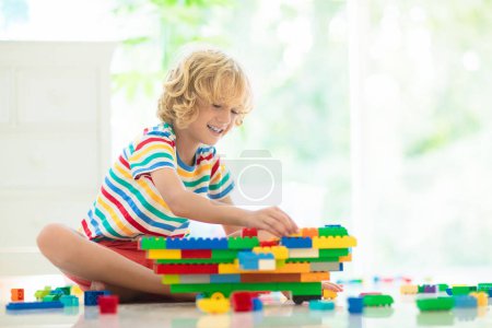Photo for Kids play with colorful blocks. Little boy building tower at home or day care. Educational toy for young child. Construction creative game for baby or toddler kid. Mess in kindergarten playroom. - Royalty Free Image