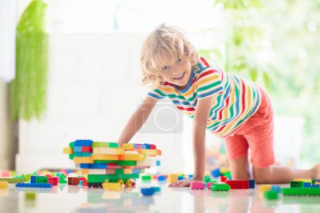 Téléchargez les photos : Les enfants jouent avec des blocs colorés. Petit garçon construisant une tour à la maison ou à la garderie. Jouet éducatif pour jeune enfant. Construction jeu créatif pour bébé ou tout-petit enfant. mess dans la salle de jeux de la maternelle. - en image libre de droit