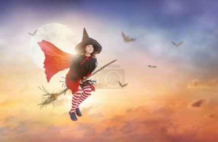 Photo for Little witch flying broom on Halloween night. Huge full moon and bats in the background. Kids trick or treat costume. Children have fun. Spooky and scary celebration. Kid dressed as evil ghost. - Royalty Free Image