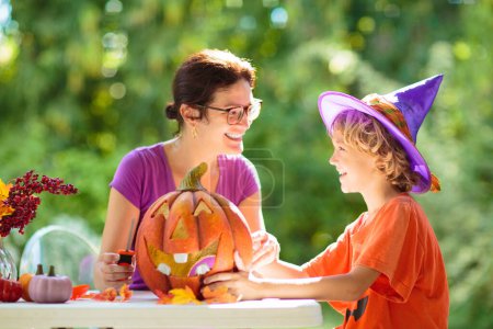 Photo for Family decorating home for Halloween celebration. Halloween arts and crafts for kids. Trick or treat decoration. Kids decorate home. Children in witch costume and hat. Spooky Halloween fun. - Royalty Free Image