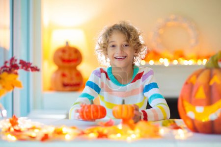 Photo for Family decorating home for Halloween celebration. Halloween arts and crafts for kids. Trick or treat decoration. Kids decorate home. Children in witch costume and hat. Spooky Halloween fun. - Royalty Free Image