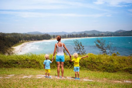Family hiking on tropical island. Mother and kids in the mountains.  Sea and mountain view from top of a hill. Parents and kids hike. Active summer vacation with children. Travel and holiday with kid