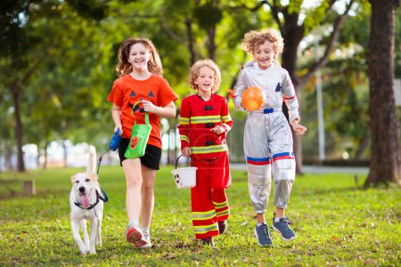 Photo for Kids trick or treat in Halloween costume. Children in colorful dress up with candy bucket on suburban street. Little boy and girl trick or treating with pumpkin lantern. Autumn holiday fun. - Royalty Free Image
