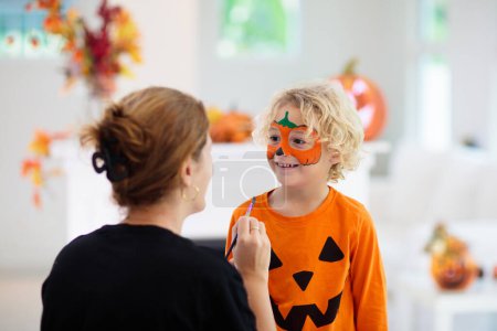 Photo for Child and mother in Halloween costume. Kids trick or treat. Face painting for party event. Little boy dressed as evil vampire with pumpkin lantern. Family celebration. Mom and son with candy. - Royalty Free Image