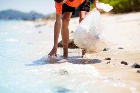 Téléchargez les photos : Des ordures en plastique. Pollution marine et océanique. Nettoyage de la plage. Un jeune homme cueillant des bouteilles en plastique usagées sur le sable. Militant écologiste ramassant des ordures. Sauvons notre Terre. Protection de la nature. - en image libre de droit