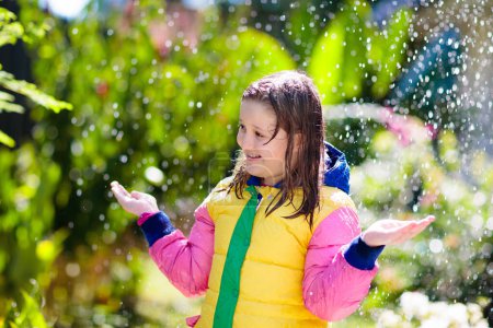 Foto de Child playing in autumn rain. Kid with umbrella. Little girl running in a park in fall season. Outdoor fun for kids by any weather. Rain waterproof wear, boots and jacket for children. - Imagen libre de derechos