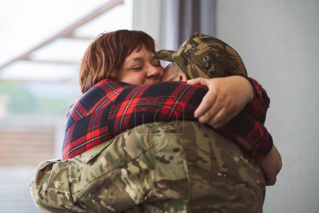 Der hispanische Soldat umarmt seine Frau, als er vom Militärdienst nach Hause zurückkehrt. Liebe und Familienkonzept. Fokus auf lateinisch reife Frau Gesicht