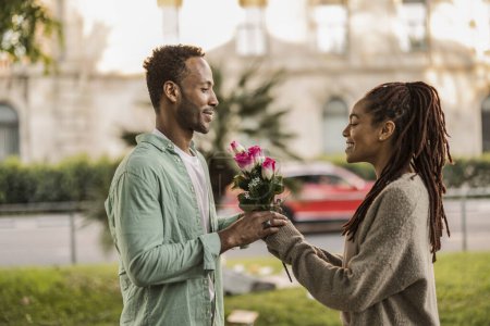 romántico par ciudad regalo ramo de flores San Valentín - hombre afroamericano da flores a su novia hispana -