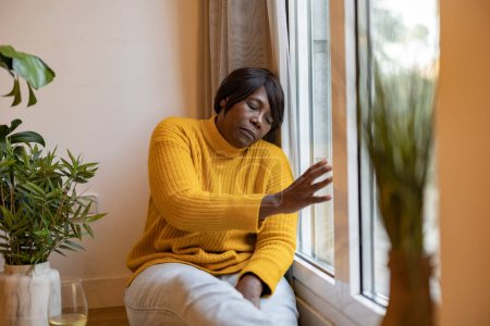 Photo for Mature woman depression home - sad african american elderly woman looking out the window - - Royalty Free Image