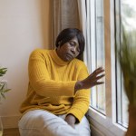 mature woman depression home - sad african american elderly woman looking out the window -