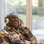 elderly pensioner at home listening to music with headphones