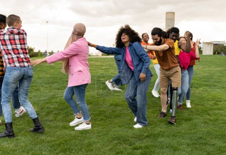 large group of diverse friends having fun together dancing in the park