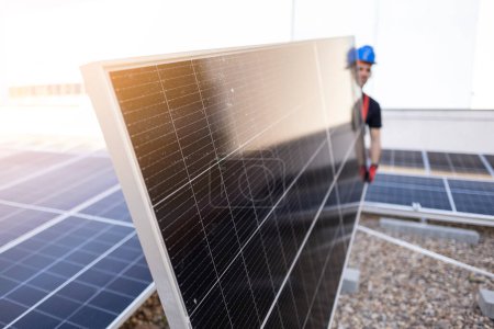 Foto de Un trabajador en el techo junto a los paneles solares que llevan un panel, vida sostenible. - Imagen libre de derechos