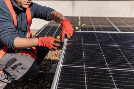 Foto de Un trabajador de la azotea arrodillado junto a paneles solares vida sostenible. - Imagen libre de derechos