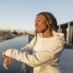 african woman looks to the horizon in the city at sunset