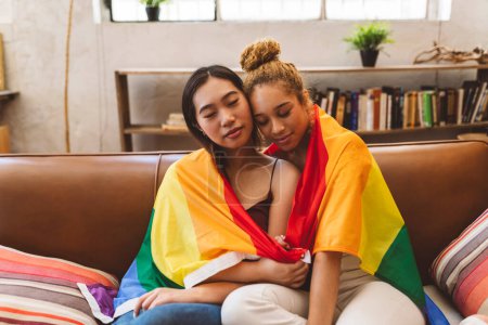 Foto de Dos jóvenes multirraciales lesbianas mujeres en casa gay orgullo bandera amor - Imagen libre de derechos