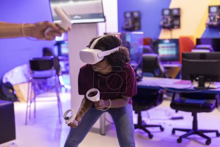 Foto de Adolescente afroamericana jugando con gafas de realidad virtual esquivando en el juego en línea en los controles de retención del ciberespacio - Imagen libre de derechos
