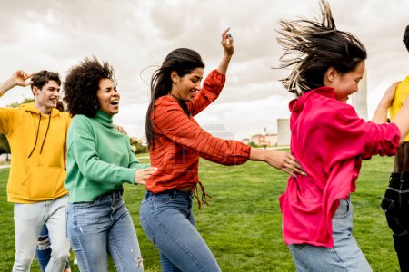 A vibrant group of young adults express their joy and unity by dancing and raising their hands in the air, celebrating a moment together outdoors.