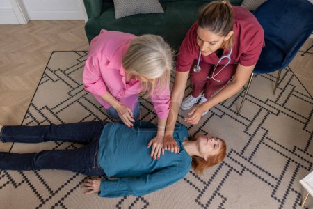 Elevated view of a CPR training with a nurse teaching two women.