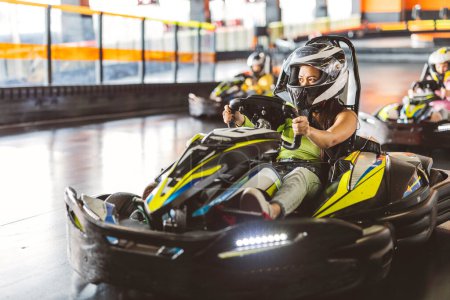 Young woman in helmet and racing gloves competing in an indoor go-kart race.