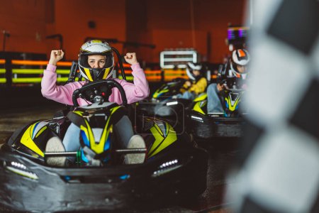 Jubilant young female raising fists in triumph after a karting race.
