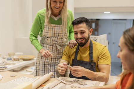 A senior female instructor and a male student share a joyful moment in a pottery class.