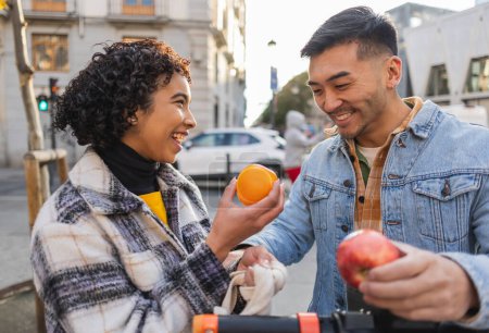 Ein Paar teilt einen verspielten Moment mit frischem Obst bei einem Stadtspaziergang.