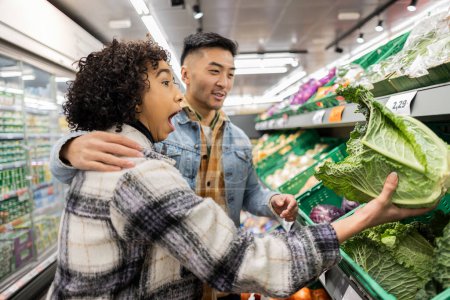 Young couple expresses excitement while picking fresh vegetables at a local grocery store.