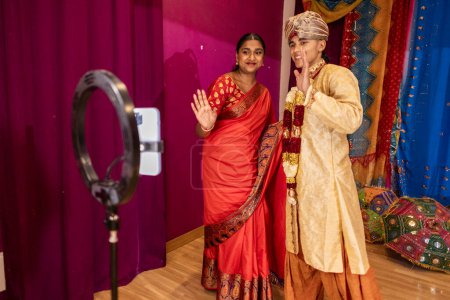 Artistas con opulento atuendo indio dando la bienvenida a una audiencia con cálidas sonrisas.