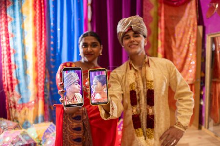 Indian performers reflect cultural richness with smartphones amid traditional decor.