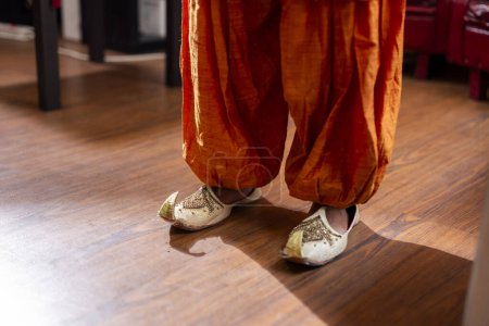 Eine Nahaufnahme aus aufwändig gestaltetem indischem Sararestoff und traditionellen Jutti-Schuhen.