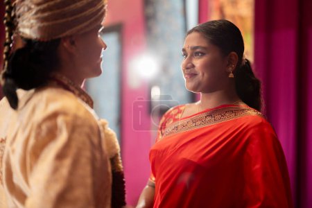Dos jóvenes indios comparten un intercambio personal, vestidos con brillantes prendas tradicionales.