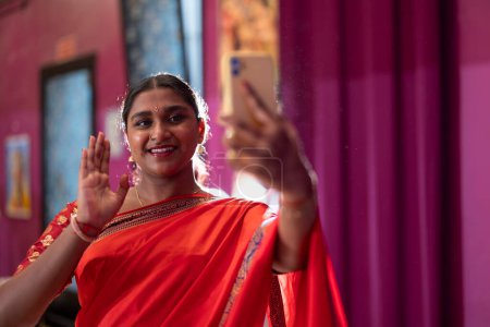 Dos alegres jóvenes indios vestidos con trajes tradicionales se toman una selfie, mostrando su atuendo cultural.