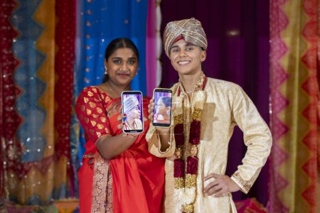 A couple in traditional Indian garments share a tech-savvy moment, capturing their festive spirit with a selfie.