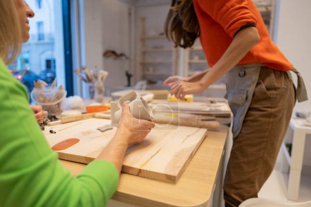 Two women engage in creative pottery making in a bright workshop.