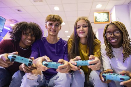 Téléchargez les photos : Un groupe joyeux d'adolescents partage un moment amusant en jouant à des jeux vidéo dans un centre de jeu local. - en image libre de droit