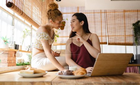 Dos jóvenes emprendedores comprometidos comparten un momento de colaboración con una computadora portátil, planeando sus próximos movimientos durante un desayuno soleado.