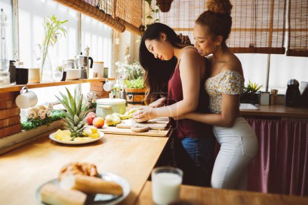 Zwei junge Frauen verbinden sich, während sie gemeinsam Früchte schneiden, umgeben vom Morgenglühen einer heimeligen Küche.
