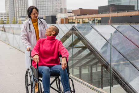 Un momento de genuina conexión mientras un médico sonriente se comunica con su paciente en silla de ruedas sobre un telón de fondo urbano.