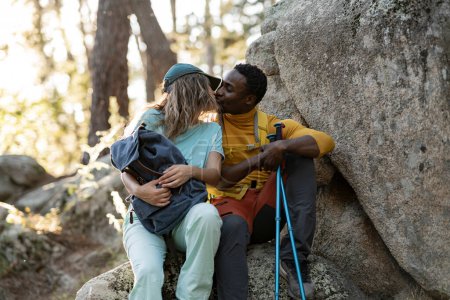 En el aislamiento de la naturaleza, una pareja de senderistas comparte un tierno beso, creando un recuerdo íntimo contra el telón de fondo del bosque.