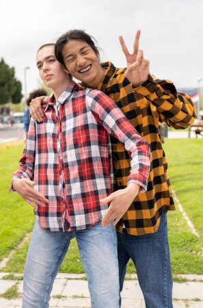 Two friends joyfully pose for a playful photo outdoors, expressing happiness with vibrant smiles and playful gestures.