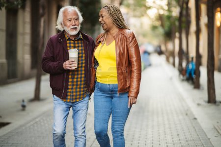 S'engager et se détendre couple de personnes âgées partageant un rire et un café tout en marchant dans une rue urbaine bordée d'arbres, profiter de la compagnie de l'autre.