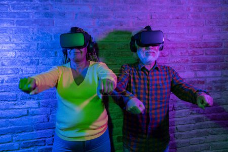 Elderly couple enjoying a virtual reality experience together, immersed in a digital world, highlighted by vibrant neon lights.