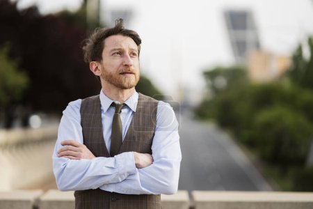 Thoughtful mature businessman in stylish vest and tie, gazing into the distance, embodying a moment of reflection in a modern cityscape.